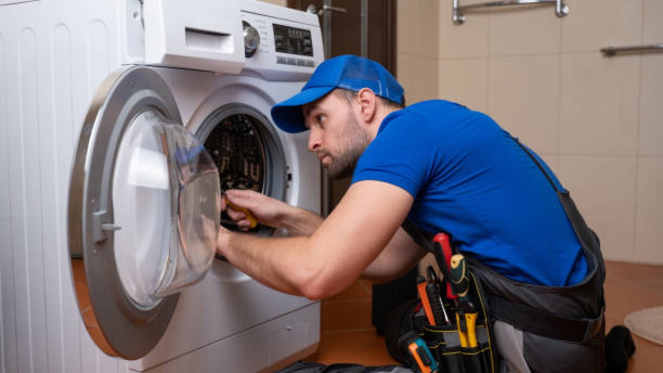 Working man plumber repairs a washing machine in home. Washing machine installation or repair. plumber connecting appliance.