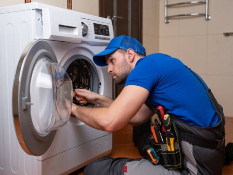 Working man plumber repairs a washing machine in home. Washing machine installation or repair. plumber connecting appliance.